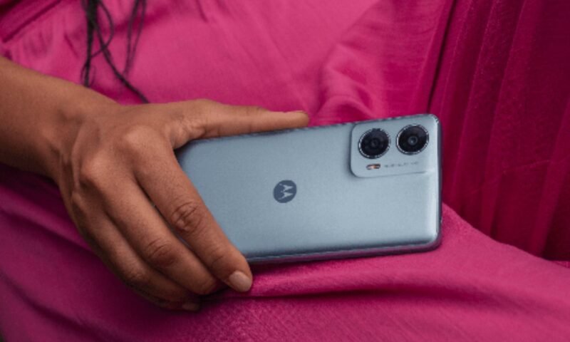 Mão feminina de pele preta usando roupa rosa segura um Motorola Moto G24 Power na cor azul celeste