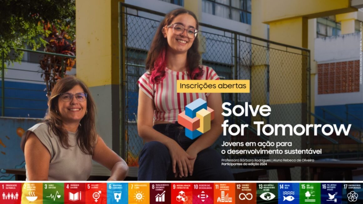 Duas mulheres sorridentes, uma sentada em uma mesa de madeira e outra no banco, em frente a um fundo desfocado com ícones coloridos dos Objetivos de Desenvolvimento Sustentável e o texto em português "Inscrições abertas Solve for Tomorrow Jovens em ação para o desenvolvimento sustentável".