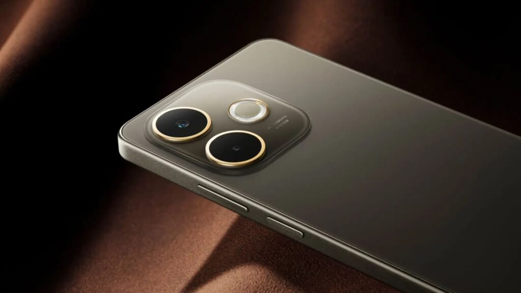 Close-up do canto traseiro de um smartphone OPPO A5 Pro 5G de cor cinza-escuro com acabamento fosco. O aparelho está deitado sobre uma superfície de couro marrom. O foco está no módulo de câmera, que possui duas lentes grandes com anéis dourados e um flash circular. A iluminação suave destaca os contornos e o design elegante do telefone.