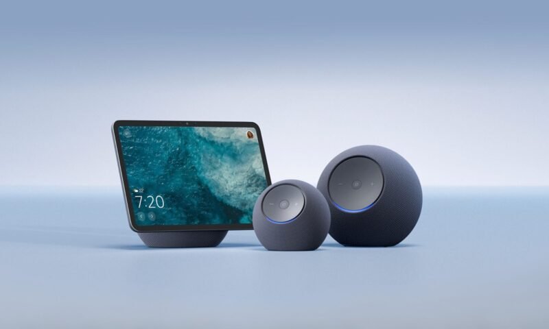 Três novos dispositivos da linha Amazon Echo 2025, todos na cor grafite e com acabamento em tecido. A imagem exibe o Echo Show com tela, o Echo Dot Max (esférico e menor) e o Echo Studio (esférico e maior).