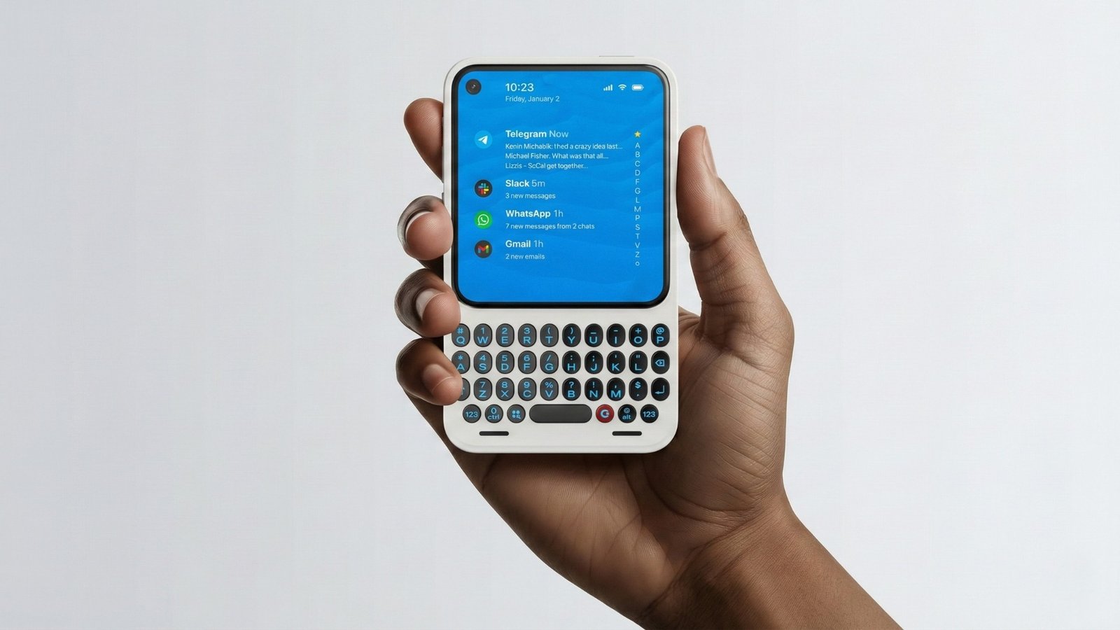 Uma fotografia em close-up mostra uma mão de pele negra segurando um smartphone Clicks Communicator na cor branca (um tom claro de cinza/off-white). O teclado QWERTY possui teclas pretas arredondadas com detalhes vermelhos nas teclas de função. A tela do celular está acesa, exibindo uma central de notificações escura com o horário 10:23 e alertas pendentes de aplicativos como Telegram, Slack, WhatsApp e Gmail. O fundo é completamente preto, destacando o dispositivo e a mão.
